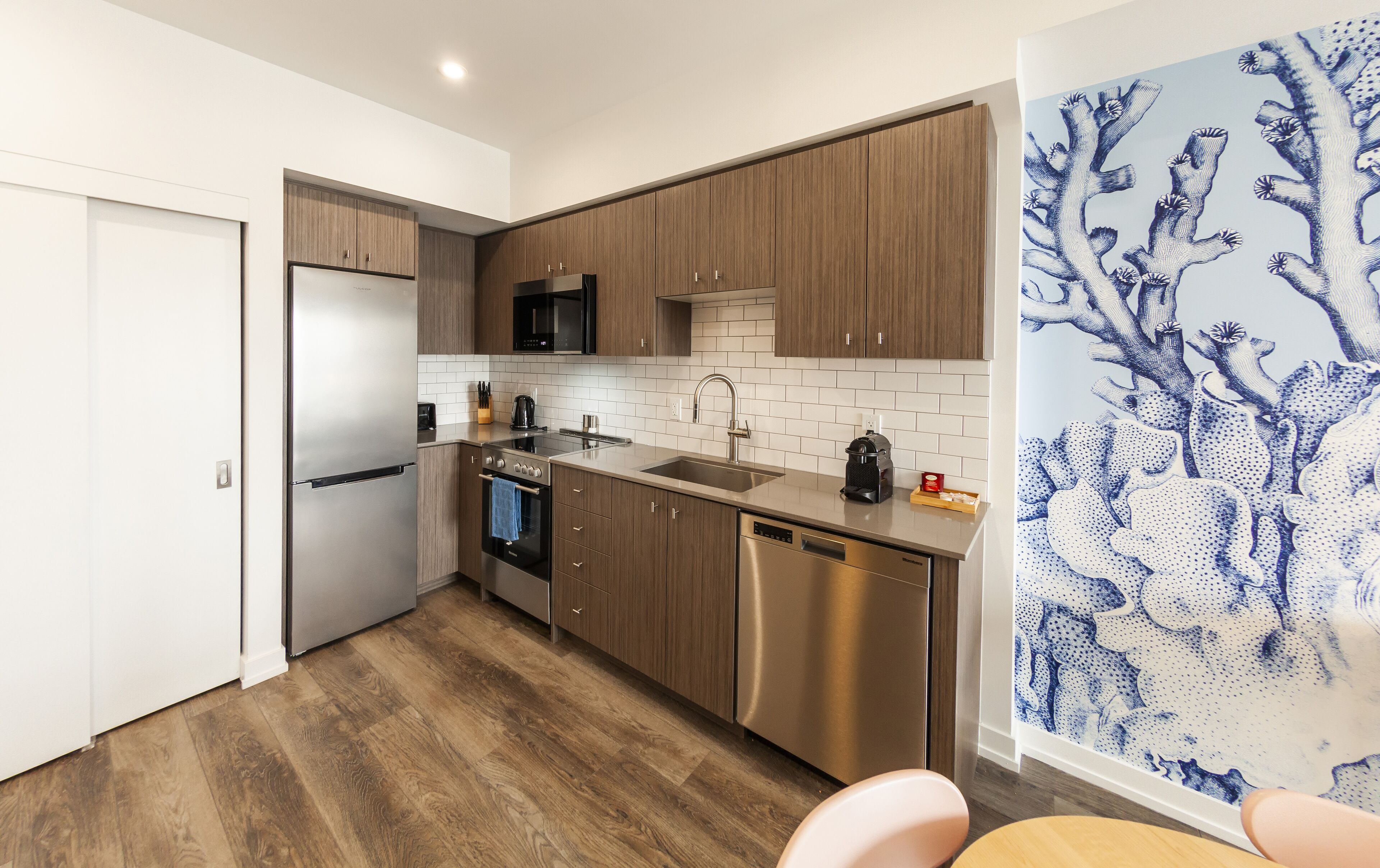 Une cuisine moderne avec des meubles en bois, des appareils électroménagers en acier inoxydable et un dosseret carrelé.