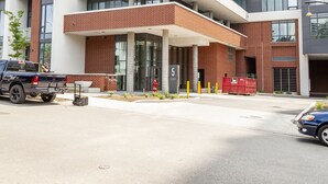 A modern building with a covered entrance, a parking area, and a visible fire hydrant. - The Laundry Rooms Station Park Kitchener (Kitchener)
