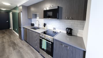 Una cocina moderna con armarios grises, un refrigerador de acero inoxidable, un microondas, una estufa y un lavabo.
