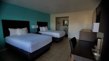 A hotel room with two beds, a desk, and a chair.