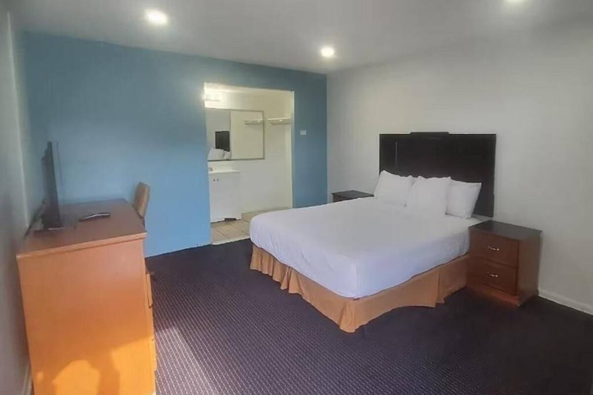 Une chambre d’hôtel comprenant un lit, un bureau, une chaise, une commode et un miroir.