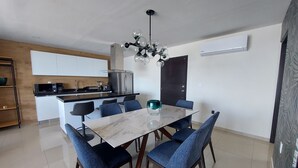 Eine moderne Küche mit einer zentralen Kochinsel, einem Essbereich mit Marmortisch und blau gepolsterten Stühlen.