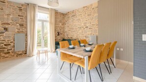 Un comedor con una mesa de madera y sillas amarillas, paredes de piedra y vistas a través de un ventanal.