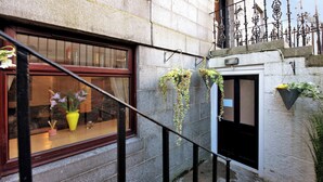 A narrow alley with a window displaying flowers and a potted plant.