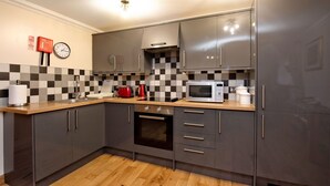 A modern kitchen with grey cabinets, a microwave, a stove, and a checkered backsplash.