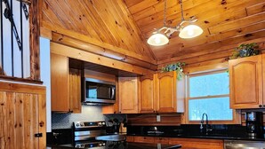 A wooden kitchen with a central island, bar stools, and stainless steel appliances.