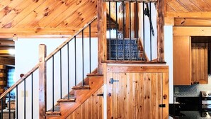 A wooden interior with a staircase leading to a loft area, a dining area with a wooden table and chairs, and a kitchen with modern appliances.