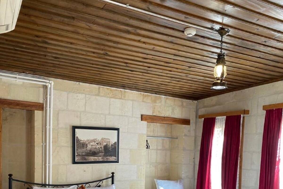 Ein Schlafzimmer mit zwei Betten, Holzboden, Steinwand und einem gerahmten Bild.