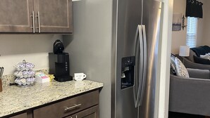 A modern kitchen with stainless steel appliances, wooden cabinets, and a granite countertop.