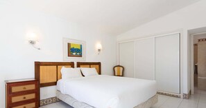 Ein Schlafzimmer mit einem Bett, Nachttischen aus Holz, einer Wandleuchte und einem gerahmten Bild.