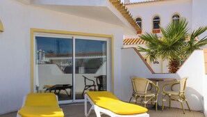 Eine Terrasse mit zwei Liegestühlen, einem Tisch und Stühlen.