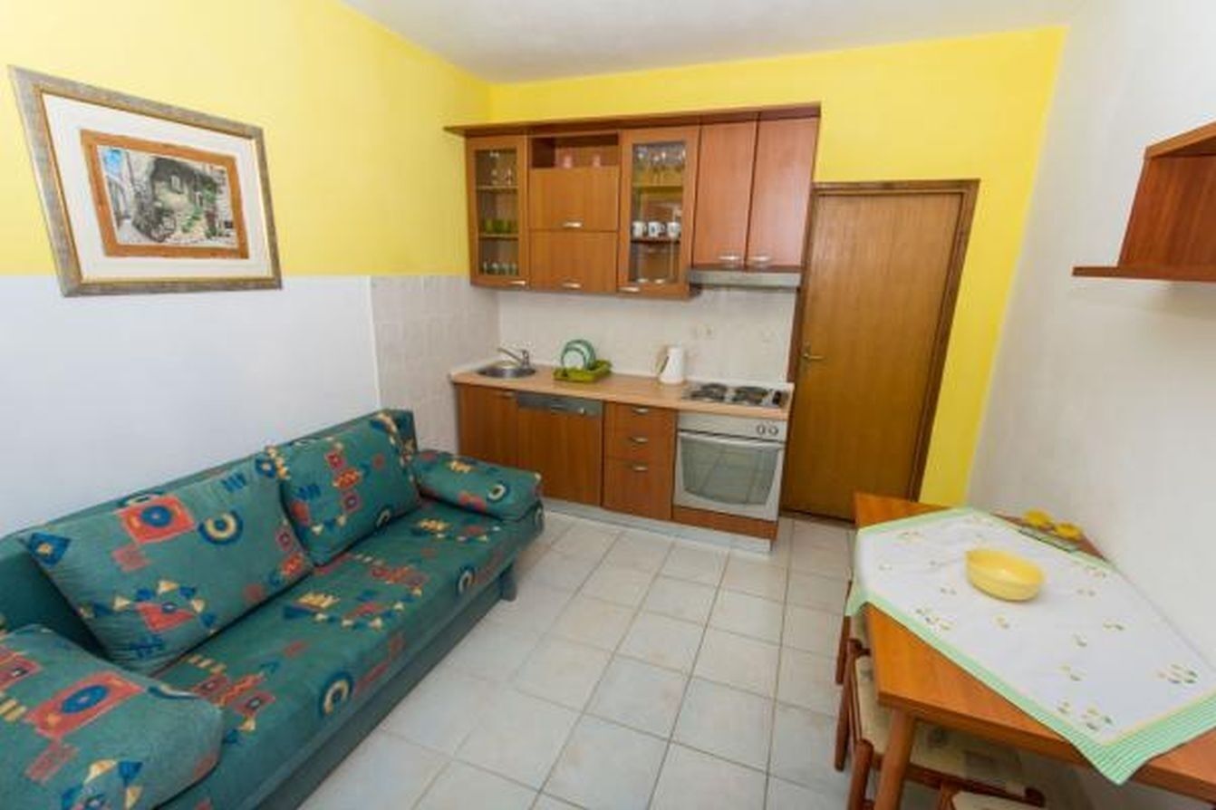 Una cocina compacta con armarios de madera, horno empotrado y una mesa de comedor con un posavasos.