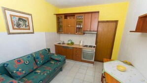 A compact kitchen with wooden cabinets, a built-in oven, and a dining table with a placemat. - Apartment in Okrug Gornji with Terrace, Air condition, WIFI, Washing machine (5167-1) (Okrug Gornji)