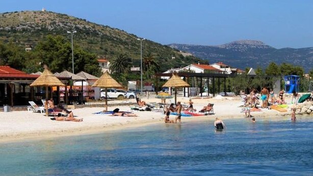 A beach with sun loungers, umbrellas, and a clear view of the sea and hills in the background. - Apartment in Okrug Gornji with Terrace, Air condition, WIFI, Washing machine (5167-1) (Okrug Gornji)