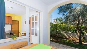 A room with a wooden table, a bench, and a view of a garden with a tree. - Apartment in Okrug Gornji with Terrace, Air condition, WIFI, Washing machine (5167-1) (Okrug Gornji)