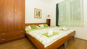A bedroom with a wooden wardrobe, a bed with green bedding, a framed picture on the wall, and a window with sheer curtains. - Apartment in Okrug Gornji with Terrace, Air condition, WIFI, Washing machine (5167-1) (Okrug Gornji)