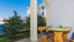 A patio with a wooden table and bench, surrounded by white walls and a view of a building. - Apartment in Okrug Gornji with Terrace, Air condition, WIFI, Washing machine (5167-1) (Okrug Gornji)