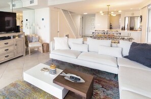 A modern living room with a white sofa, a coffee table with a fish decoration, and a television on a cabinet.