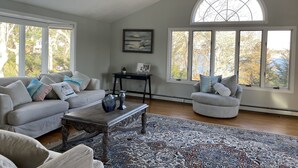 A spacious living room with a large window, a fireplace, and a cozy seating area. - Buzzards bay hide away (Bourne)