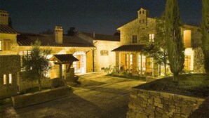 A stone building with a courtyard, featuring arched doorways and a tiled roof. - Villa Nocciolo in most Exclusive Borgo in Tuscany (Pian di Sco)