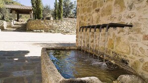 A stone water feature with a fountain, surrounded by a stone wall and steps leading to a covered area. - Villa Leccino in most Exclusive Borgo in Tuscany (Pian di Sco)