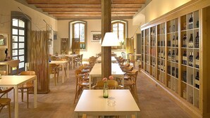 A dining area with wooden tables and chairs, a central column, and wine display cases along the walls. - Villa Leccino in most Exclusive Borgo in Tuscany (Pian di Sco)