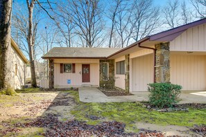 A single-story house with a front porch, a stone pillar, and a small bush.