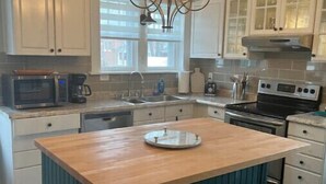 Una cocina con una isla central, armarios blancos, una estufa y un microondas.