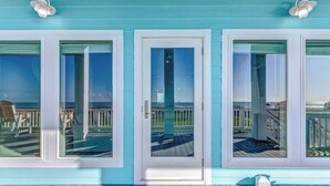 A coastal property with a turquoise exterior, a wooden deck, and a view of the ocean.