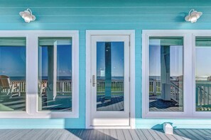 A coastal property with a turquoise exterior, a wooden deck, and a view of the ocean.