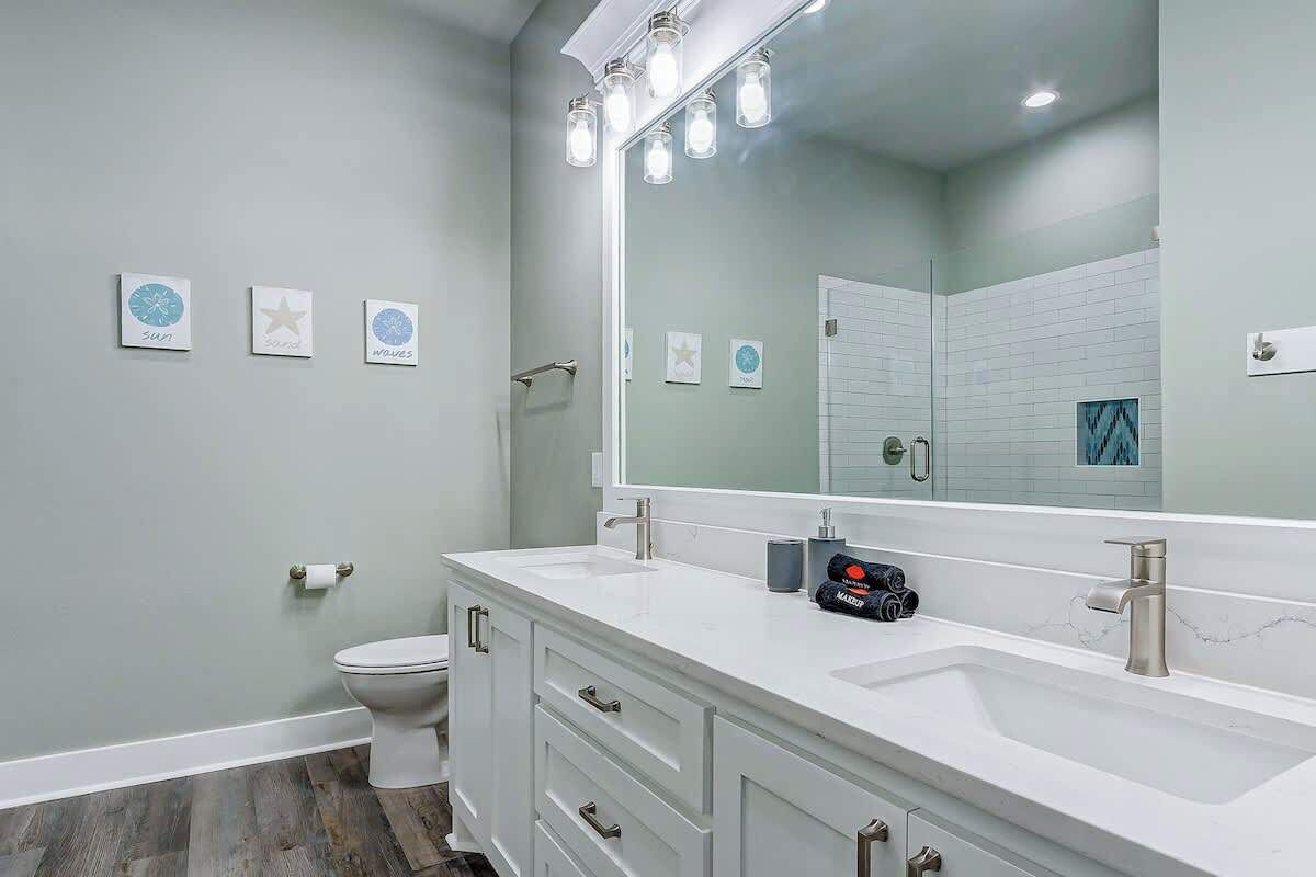 Une salle de bain moderne avec un meuble-lavabo blanc, un grand miroir et des toilettes.