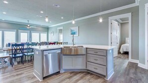 A modern kitchen with a built-in dishwasher, a stainless steel sink, and a dining area with a table and chairs.