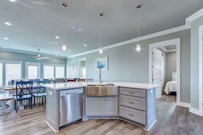 A modern kitchen with a built-in dishwasher, a stainless steel sink, and a dining area with a table and chairs.