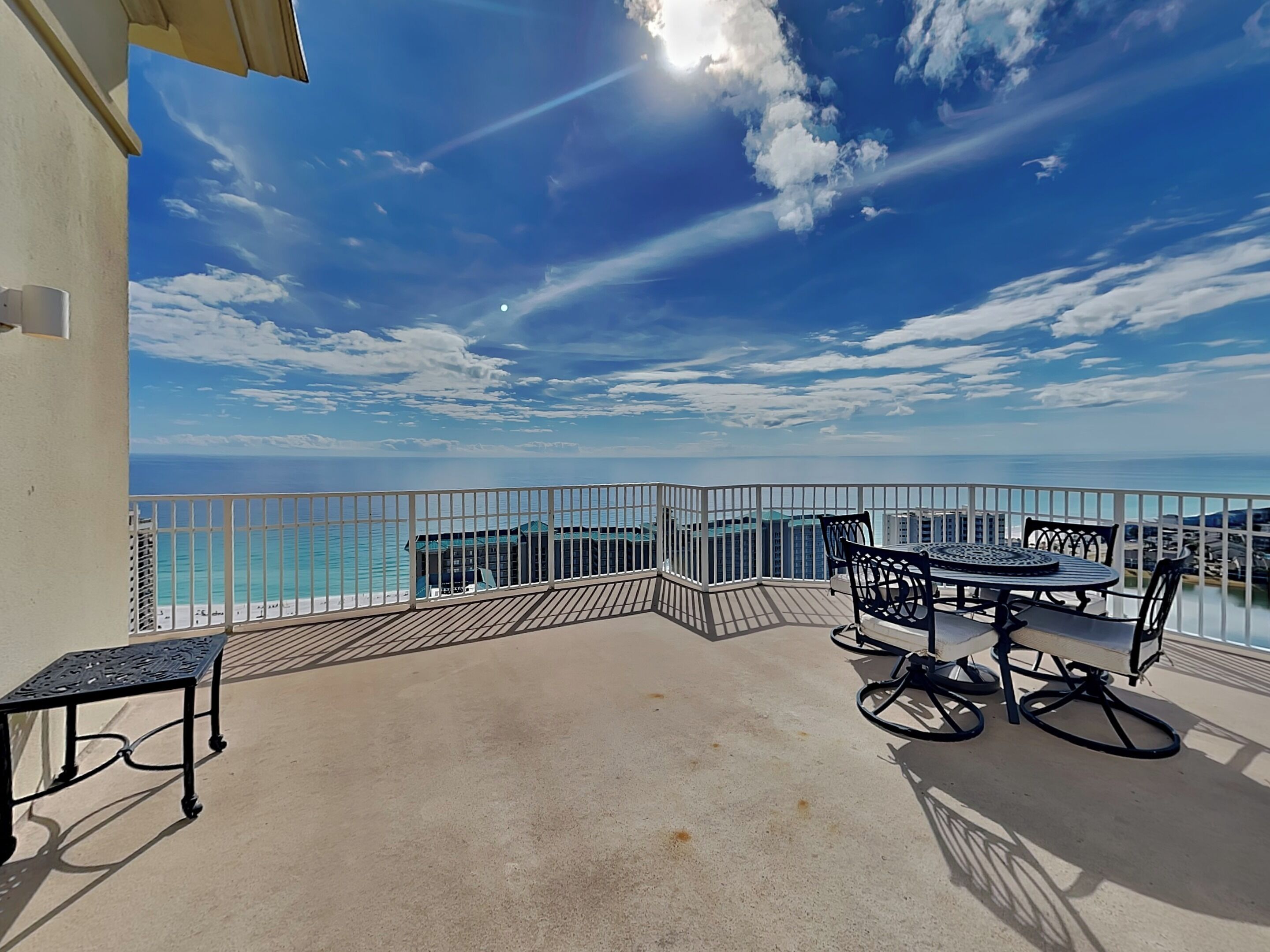 Un balcon avec une table et des chaises, donnant sur une plage et l’océan.