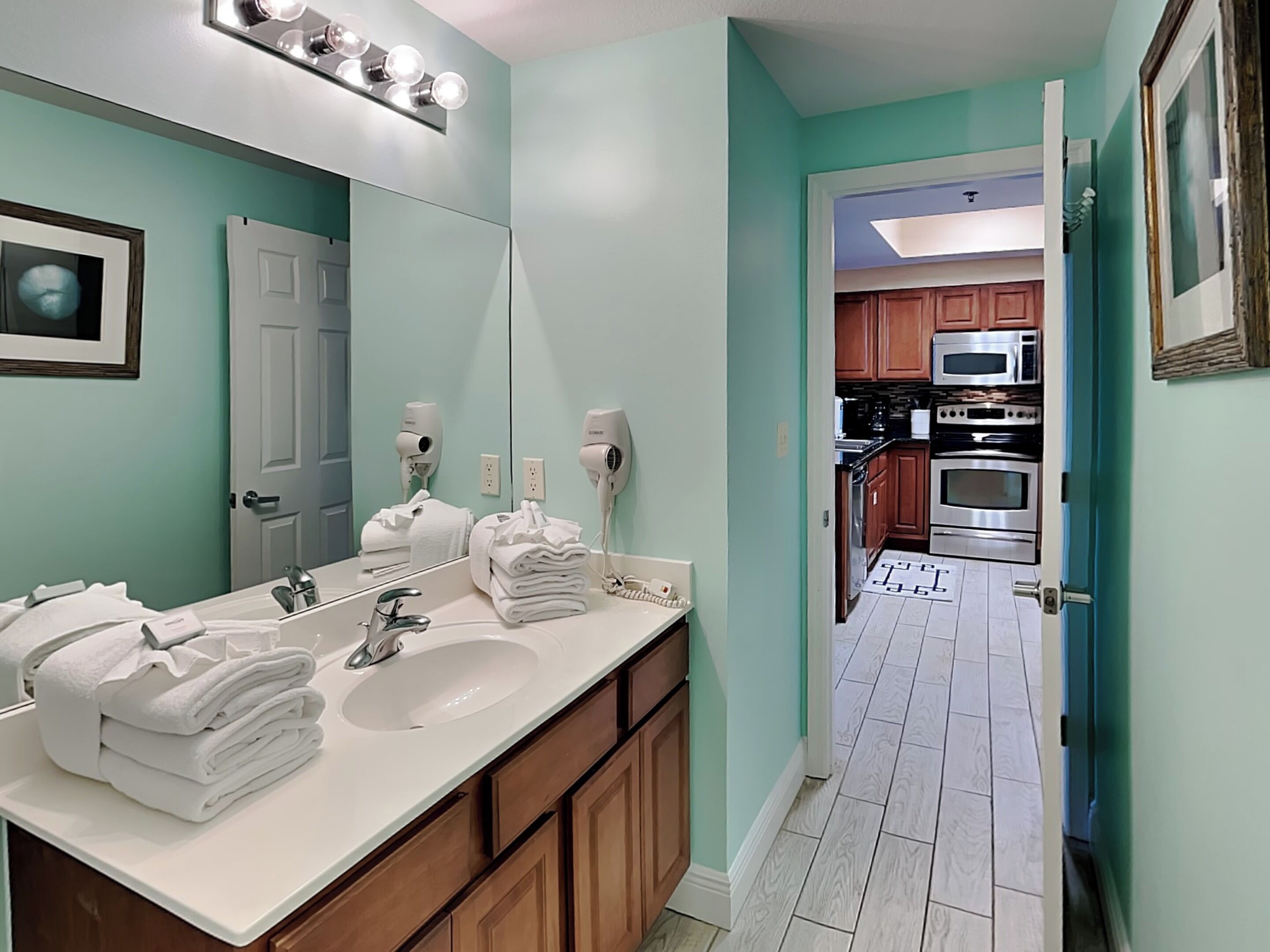 A bathroom with a sink, mirror, and two hair dryers.