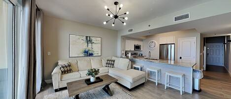 A modern kitchen with a central island, a dining area with a sofa, and a living room with a coffee table.