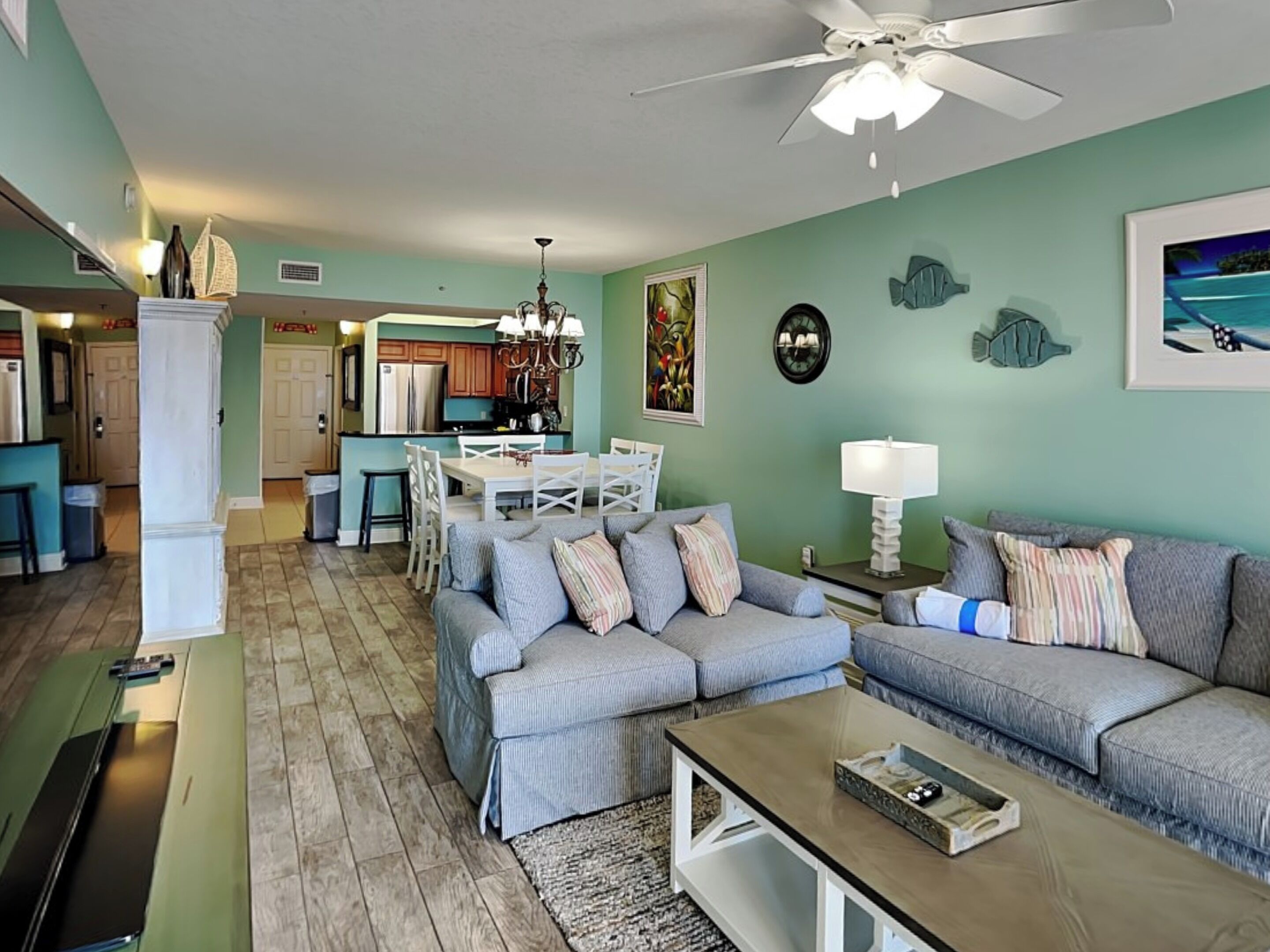 A living room with a grey sofa, a coffee table, and a dining area with a white table and chairs.