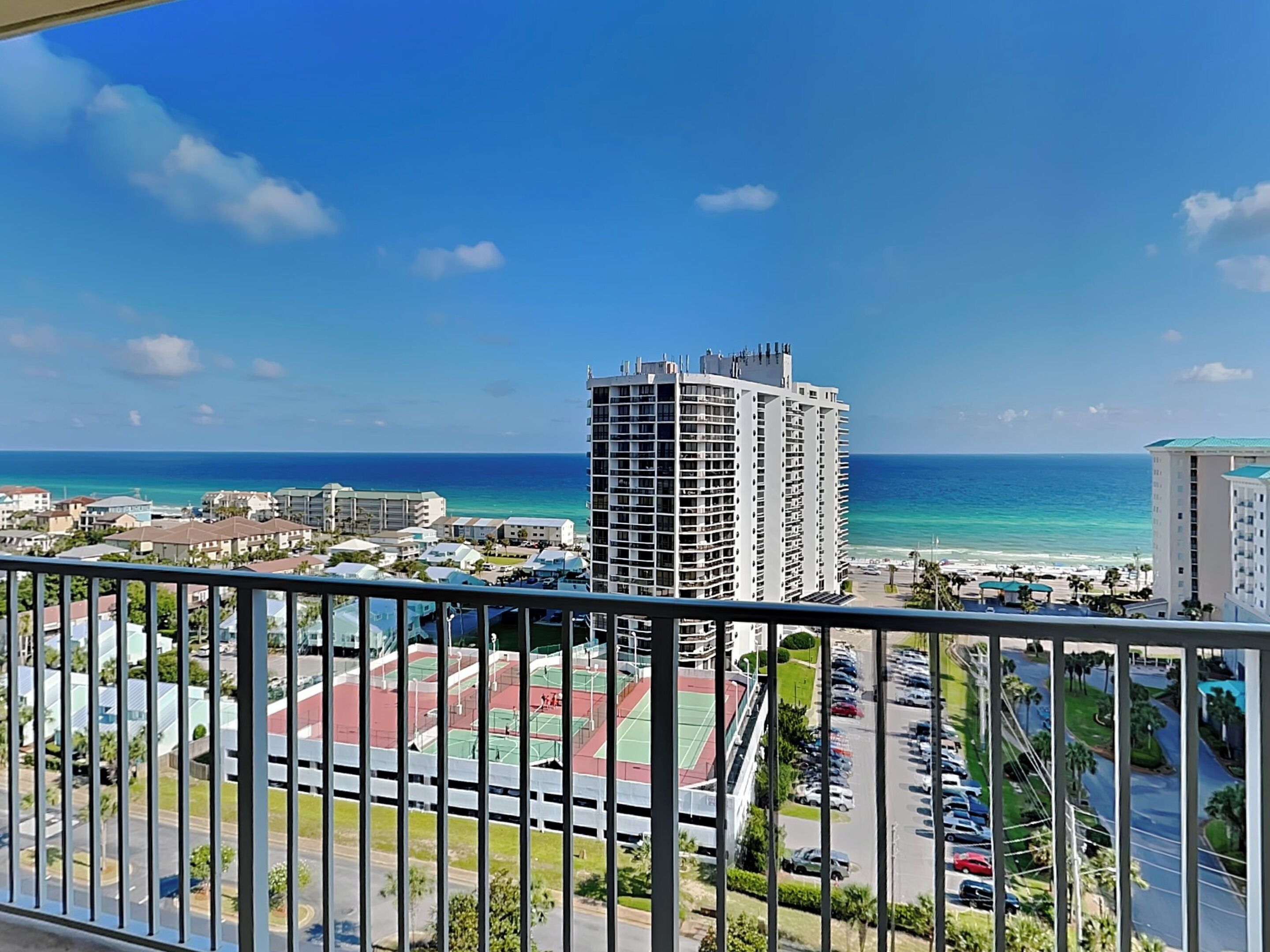 A high-rise building with a view of the ocean and a parking lot below.