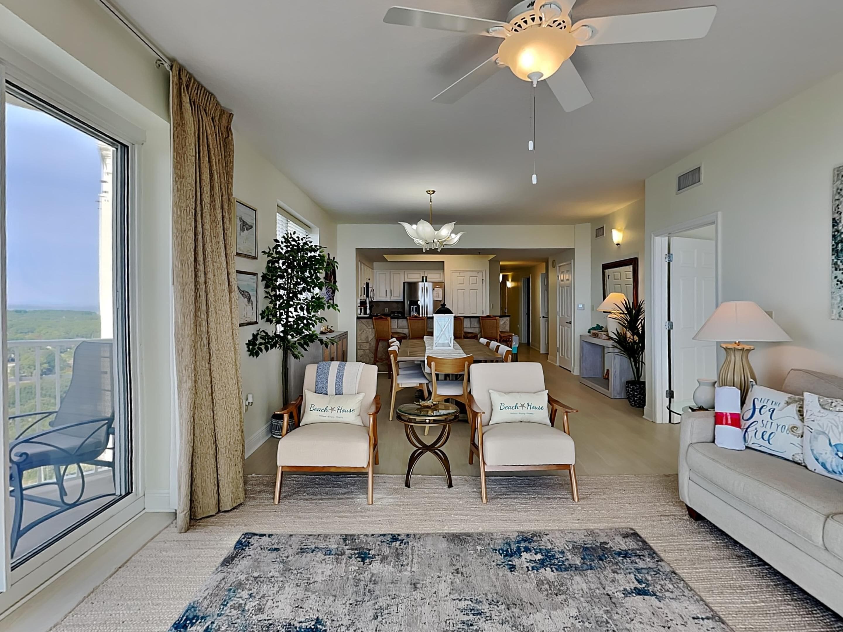 A spacious living area with a large window, a ceiling fan, and a view of the outdoors.