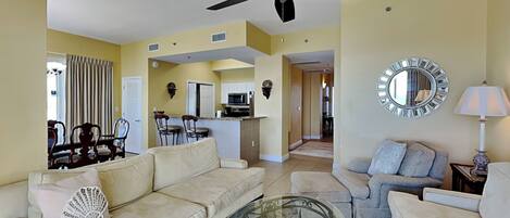 A living room with a beige sofa, a glass coffee table, and a ceiling fan.
