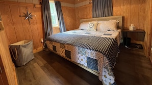 Ein Schlafzimmer mit Holzwänden, einem Bett, Vorhängen, einer Stern-Wanddekoration und einem Nachttisch mit Taschentuchbox.