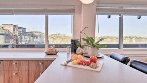 A modern kitchen with a large window, a cutting board with vegetables, and a potted plant. - Floating condo 'C' on Sausalito's Richardson Bay (Mill Valley)