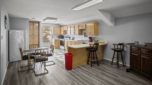 Une cuisine moderne avec des meubles en bois, un îlot central, des tabourets de bar et une table à manger avec des chaises.