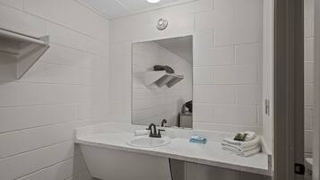 A modern bathroom with white tiled walls, a white sink, a mirror, and a towel rack.