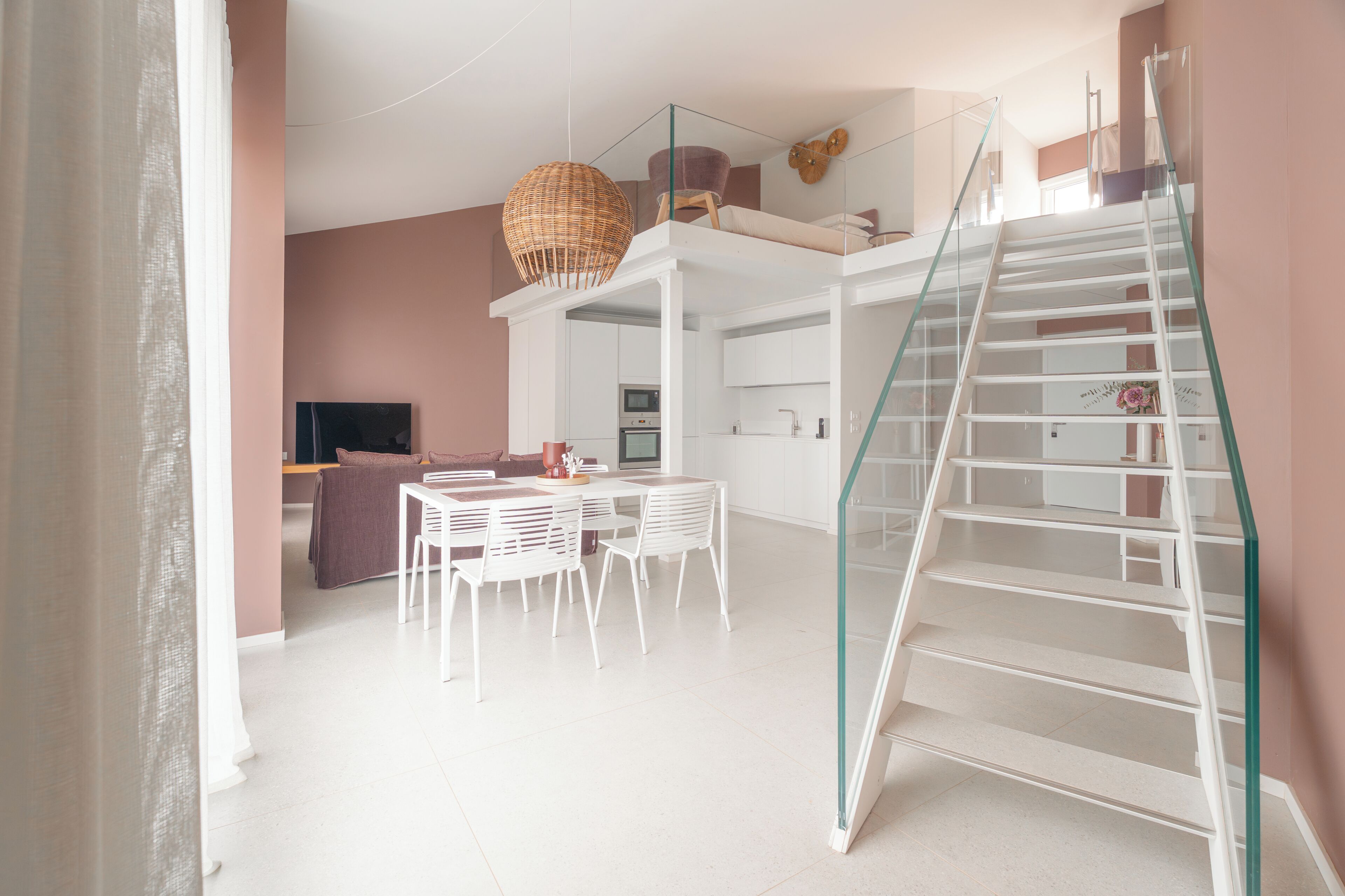Un intérieur moderne comprenant un escalier, un coin repas, une cuisine et un canapé.