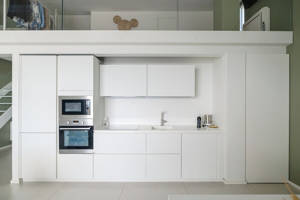 A modern kitchen with built-in appliances, a microwave, oven, and a sink. - Montegrottone Nature Retreat (Polignano a Mare)