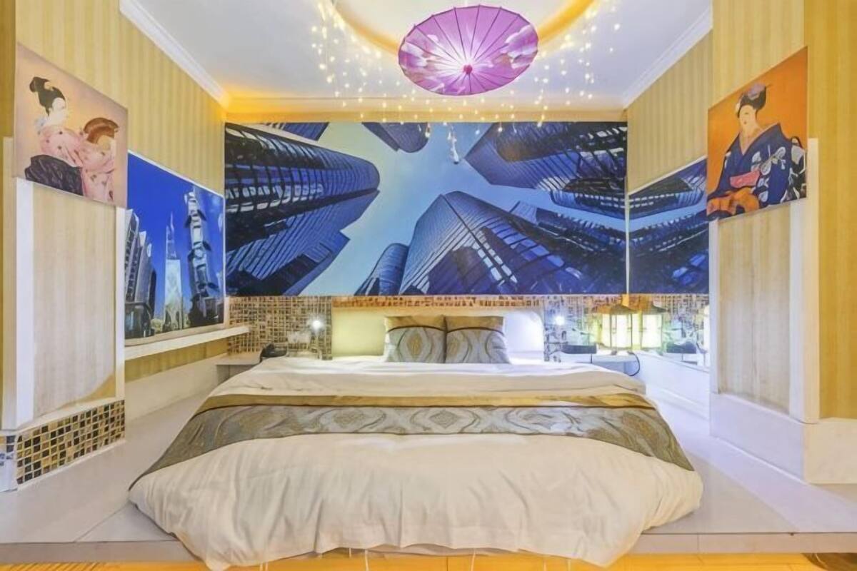 A bedroom with a bed, a large wall mural, and a ceiling light fixture.