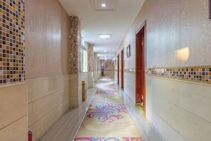 A hotel corridor with patterned walls, a decorative carpet, and doors leading to rooms. - Jiahua Business Hotel (Guangzhou North Railway Station Huacheng Road Subway Station) (Guangzhou)