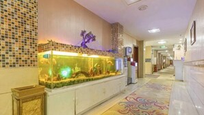 A hotel lobby with a decorative fish tank, a patterned floor, and a corridor leading to other rooms. - Jiahua Business Hotel (Guangzhou North Railway Station Huacheng Road Subway Station) (Guangzhou)