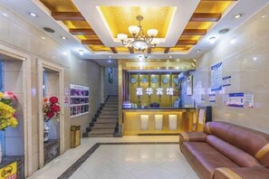 Zona de recepción de un hotel con mostrador, escalera y área de descanso.